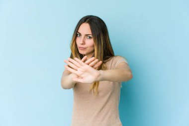 Mavi arka planda izole edilmiş genç beyaz kadın elini uzatmış, dur işareti göstererek seni engelliyor..