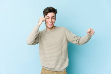 Genç beyaz adam mavi arka planda izole edilmiş dans ediyor ve eğleniyor..