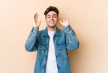 Beyazlı genç bir adam bej arka planda izole edilmiş neşeli bir şekilde gülüyor. Mutluluk kavramı.