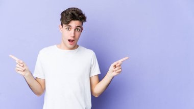 Mor arka planda izole edilmiş genç beyaz adam farklı kopya alanlarını gösteriyor, birini seçiyor, parmağıyla gösteriyor..