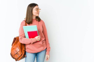 Beyaz arka planda izole edilmiş beyaz tenli genç beyaz kadın sola bakıyor, yandan poz veriyor..