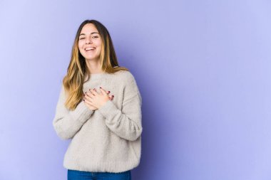 Mor arka planda soyutlanmış beyaz bir kadın. Gülüyor, elini kalbe koyuyor, mutluluk kavramını koruyor..