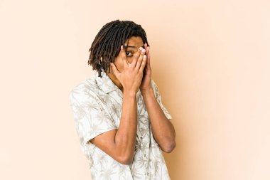 Genç Afrikalı Amerikalı Rasta adam parmaklarının arasından korkmuş ve gergin bir şekilde göz kırpıyor..