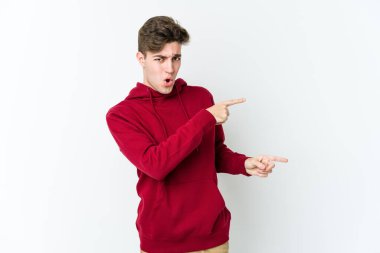 Beyaz arka planda izole edilmiş genç beyaz bir adam işaret parmağıyla fotokopi alanını işaret ederek heyecan ve arzusunu ifade ediyor..