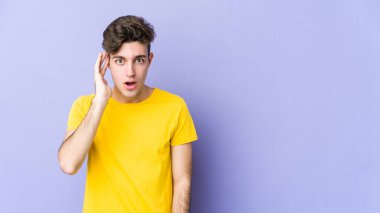 Mor arka planda izole edilmiş genç beyaz adam yüksek sesle bağırıyor, gözleri açık ve elleri gergin tutuyor..