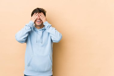 Genç, havalı adam elleriyle gözlerini kapatıyor, gülümseyerek bir sürpriz bekliyor..