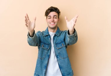 Beyazlı genç adam bej arka planda izole edilmiş kameraya sarıldığı için kendinden emin hissediyor..