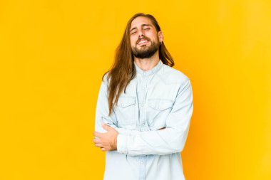 Uzun saçlı genç adam kendine güvenen, kararlılıkla kollarını kavuşturan..