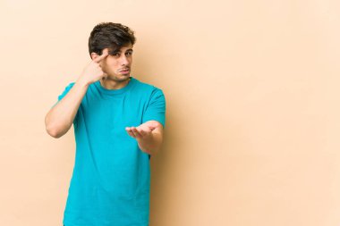 Genç havalı adam elinde bir ürünü tutuyor ve gösteriyor..