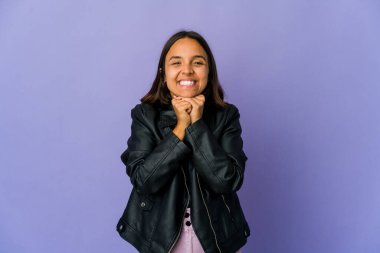 Genç melez kadın ellerini çenesinin altında tutuyor, mutlu bir şekilde yan tarafa bakıyor..