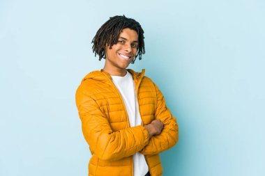 Kendine güveni tam genç melez bir adam, kararlılıkla kollarını kavuşturuyor..