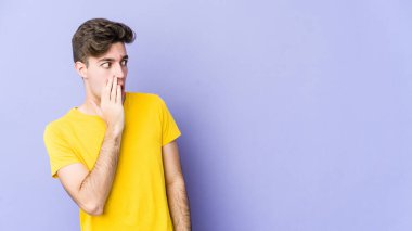 Mor arka planda izole edilmiş genç beyaz adam gördüğü bir şey yüzünden şoka uğruyor..