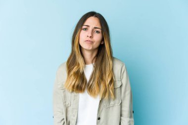 Genç beyaz kadın mavi arka planda izole edilmiş üzgün, ciddi yüzlü, mutsuz ve hoşnutsuz..