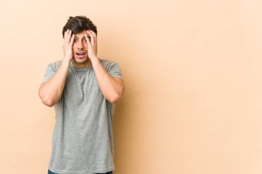 Genç havalı adam yüzünün yarısını avuç içiyle kaplayarak eğleniyor..