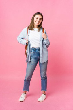 Pembe arka planda tek başına okula giden genç bir kız öğrenci.