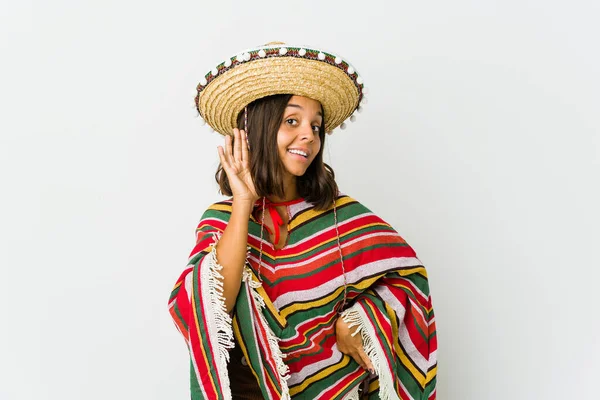 Young mexican woman isolated on white background trying to listening a gossip.