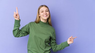 Mor arka planda izole edilmiş genç sarışın kadın farklı kopya alanlarını gösteriyor, birini seçiyor, parmaklarıyla gösteriyor.