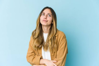 Mavi arka planda izole edilmiş genç beyaz kadın tekrarlanan bir görevden yoruldu..