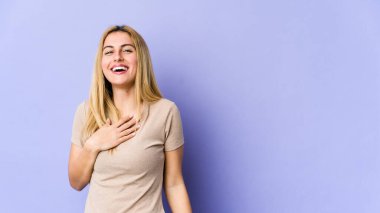 Sarışın, beyaz bir kadın elini göğsünde tutarak kahkahalar atıyor..