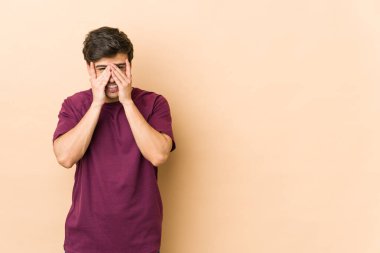 Genç havalı adam kameraya parmaklarıyla göz kırpıyor, utanarak yüzünü kapatıyor..