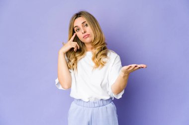 Genç, beyaz, sarışın bir kadın elinde bir ürün tutuyor..