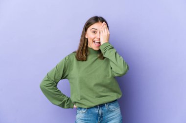 Beyaz bir kadın yüzünün yarısını avuç içiyle kaplayarak eğleniyor..