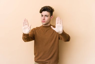 Beyazlı genç bir adam bej arka planda izole edilmiş, elini uzatmış, dur işareti göstererek seni engelliyor..