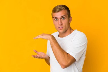 Kafkasyalı yakışıklı bir adam iki eliyle bir şey tutuyor, ürün sunumu..