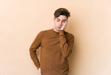 Bej arka planda izole edilmiş beyaz bir genç. Sıkılmış, yorgun ve dinlenmeye ihtiyacı var..