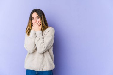 Mor arka planda izole edilmiş, elleri endişeli görünen genç beyaz bir kadın..