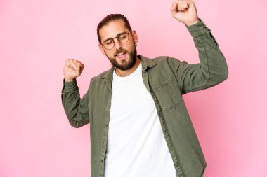 Uzun saçlı genç adam özel bir günü kutluyor, atlıyor ve enerji dolu kollarını kaldırıyor..