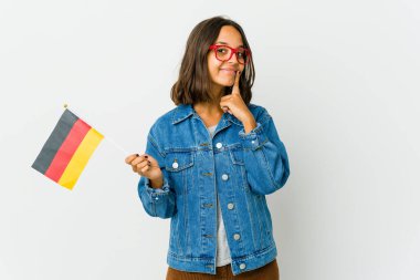 Elinde Alman bayrağı olan genç Latin bir kadın beyaz arka planda izole edilmiş ve iki seçenek arasında şüphe duyuyor..