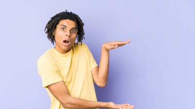 Genç Afro-Amerikan Rasta adamı ellerinin arasında bir kopya alanı tutarken şok oldu ve hayrete düştü..