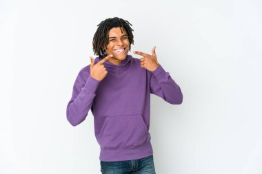 Genç Afrikalı Amerikalı Rasta adam gülümsüyor, parmaklarını ağıza doğrultuyor..