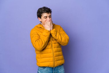 Genç, havalı bir adam bir şeye gülüyor, elleriyle ağzını kapatıyor..