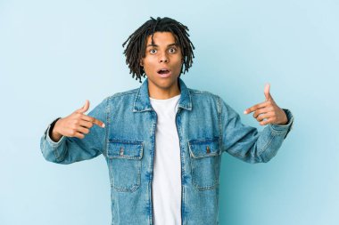 Kot ceket giyen genç siyahi adam parmaklarıyla işaret ediyor, pozitif duygu..