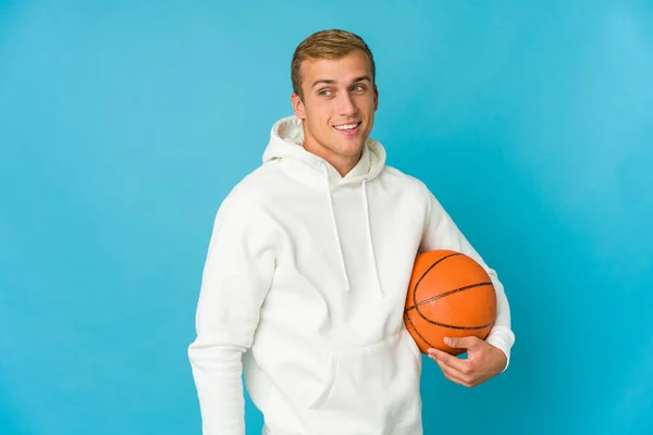 Mladý Běloch Hraje Basketbal Izolovaný Modrém Pozadí Dívá Stranou Úsměvem — Stock fotografie