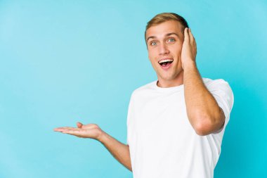 Beyaz tenli yakışıklı bir adam avucunun içinde fotokopi masası tutuyor, el üstünde tutuyor. Şaşırmış ve mutlu..