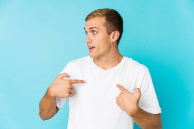 Genç, beyaz, yakışıklı bir adam parmağını gösterip, gülümseyerek şaşırdı..