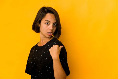 Genç İspanyol kadın sarı noktalarda izole edilmiş, başparmak uzakta, gülüyor ve kaygısız..
