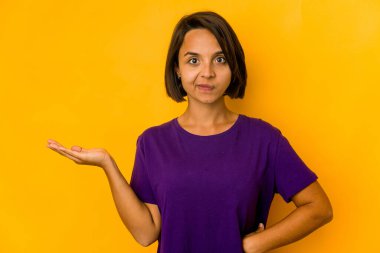 Sarıda izole edilmiş genç İspanyol kadın bir avuç içinde fotokopi alanı gösteriyor ve belinde başka bir el tutuyor..