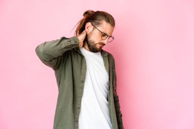 Uzun saçlı genç adam stresten dolayı boyun ağrısı çekiyor, masaj yapıyor ve eliyle dokunuyor..