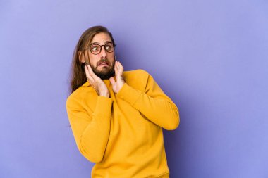 Uzun saçlı genç adam korkmuş ve korkmuş görünüyor..