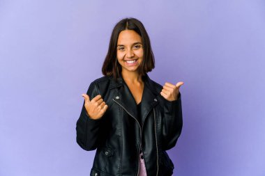 Genç melez kadın iki parmağını da kaldırıyor, gülümsüyor ve kendinden emin..