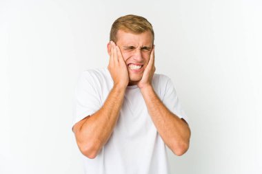 Genç, beyaz, yakışıklı adam kulaklarını elleriyle kapatıyor..