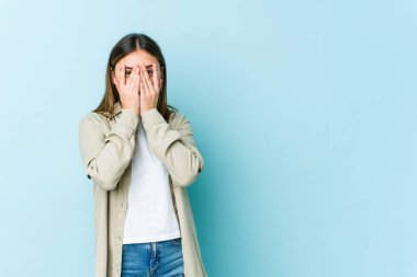 Genç beyaz kadın kameraya parmaklarıyla göz kırpıyor, utanarak yüzünü kapatıyor..