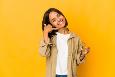 Genç İspanyol kadın eski bir anahtar tutuyor. Cep telefonu hareketini parmaklarıyla gösteriyor..