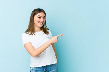 Beyaz bir kadın gülümsüyor ve boş alanda bir şeyler gösteriyor..