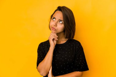 Genç İspanyol kadın sarı düşüncelere dalıp yukarı bakıyor, yansıtıyor, düşünüyor, fantezi kuruyor..