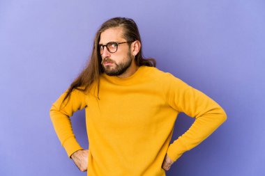 Uzun saçlı genç adam şaşkın, kuşkulu ve kararsız görünüyor..